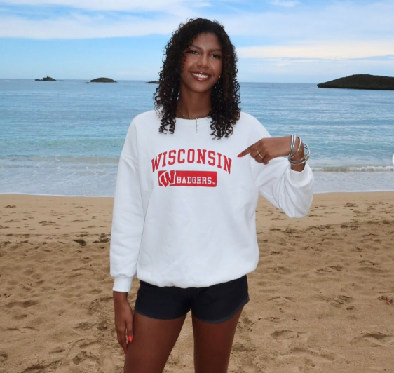 Decelise Champion stands on a beach wearing a Wisconsin Badgers sweatshirt